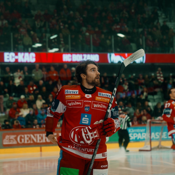 Eishockeyspieler im Dress des EC-KAC Klagenfurt mit Schläger im Eisstadion vor Zuschauern