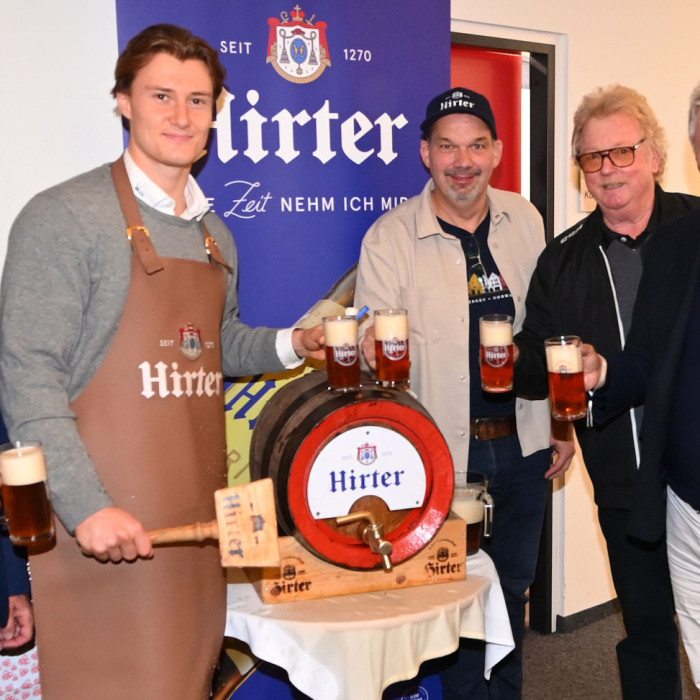 Männer mit Biergläsern und einem Bierfass vor Hirter-Logo